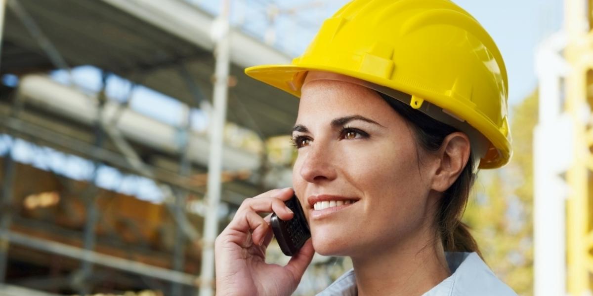 A woman on a construction site with a GroupTalk phone in a PTT group call