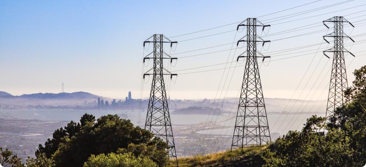 High-voltage power pylons on mountain landscape.