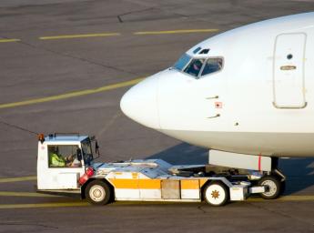 Airport personnel pushing plane into hangar for storage.