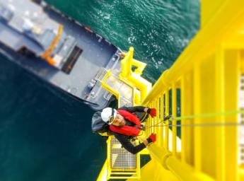 Offshore wind turbine worker ascending ladder.