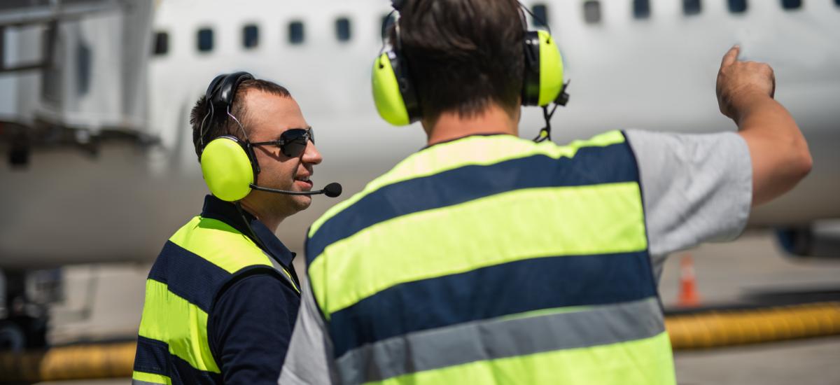 Airport worker with Peltor PTT earmuff at gate.