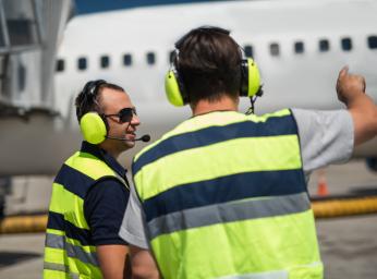 Airport worker with Peltor PTT earmuff at gate.