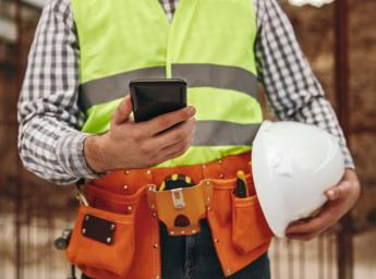 Worker on construction site communicating with team via smartphone.