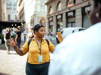 Woman tour guide giving information to tourists on city street.