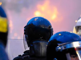 Police officers observing crowd rioting and van on fire in Belfast.