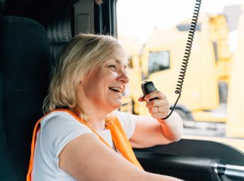 Female truck driver talking in two way radio to her work team