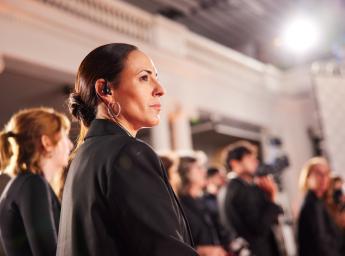 Woman guard with listen-only communication headset.