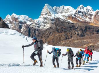 Ski guide leading tourists on mountain slope.