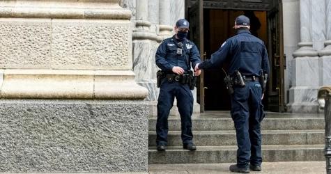 Two police officers / guards working together outside a gate