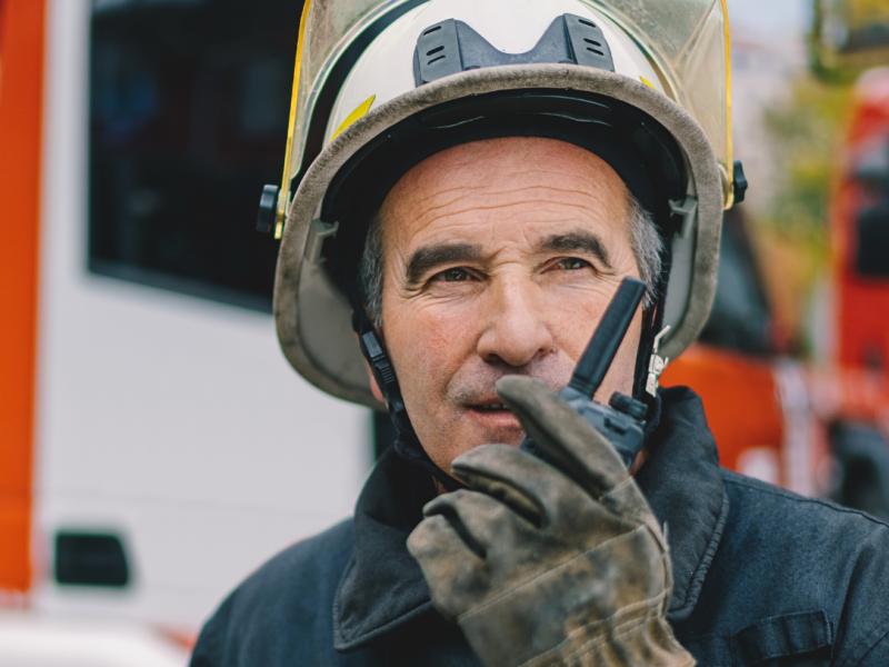 Two airport workers talking on a walkie talkie two way radio while talking to each other